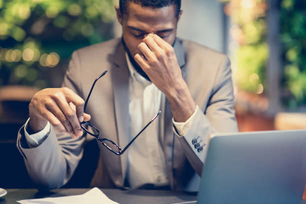 In Need of Massage Problems At Work. Tired Black Businessman Massaging His Nose Bridge Holding Glasses Working In Restaurant