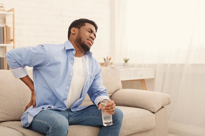 young-black-man-back-pain-home-young-african-american-man-back-pain-pressing-hip-painful-expression-sitting-136806419 young-black-man-back-pain-home-young-african-american-man-back-pain-pressing-hip-painful-expression-sitting-136806419